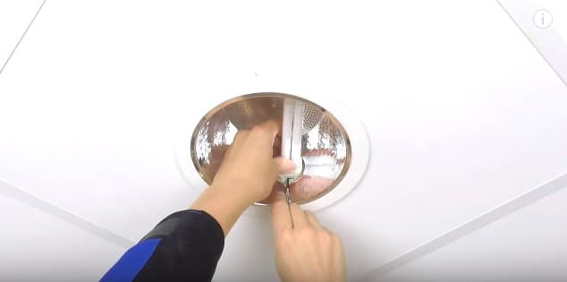 An LED downlight being installed in a plasterboard ceiling
